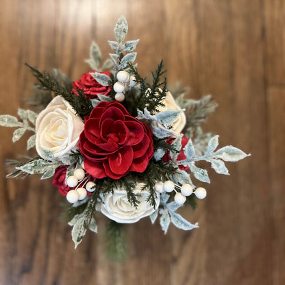 Bouquet of red and white flowers with greenery against a wooden background