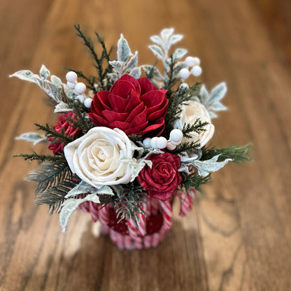 Bouquet of red and white flowers in a clear vase on a wooden surface