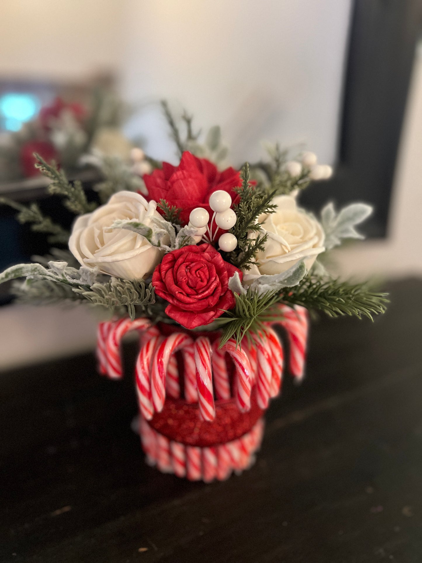 Decorative flower arrangement in a candy cane-themed vase on a dark surface.